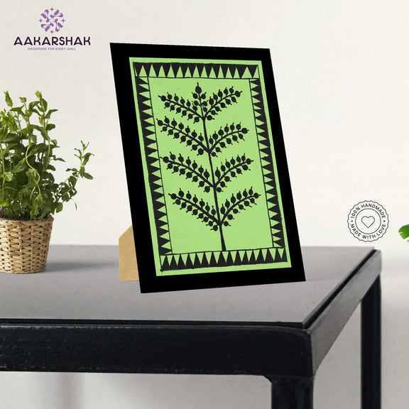 Framed artwork with green background and black tree warli painting